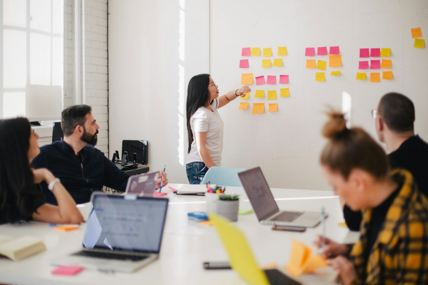 Group of people working together around a table in a workshop (stock photo, not the Instalogic team)